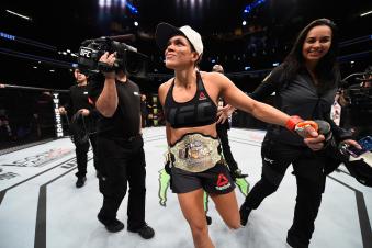 Amanda Nunes walks around the cage with the championship belt after beating Ronda Rousey in their UFC women's bantamweight championship bout during the UFC 207 event at T-Mobile Arena on December 30, 2016 in Las Vegas, Nevada.